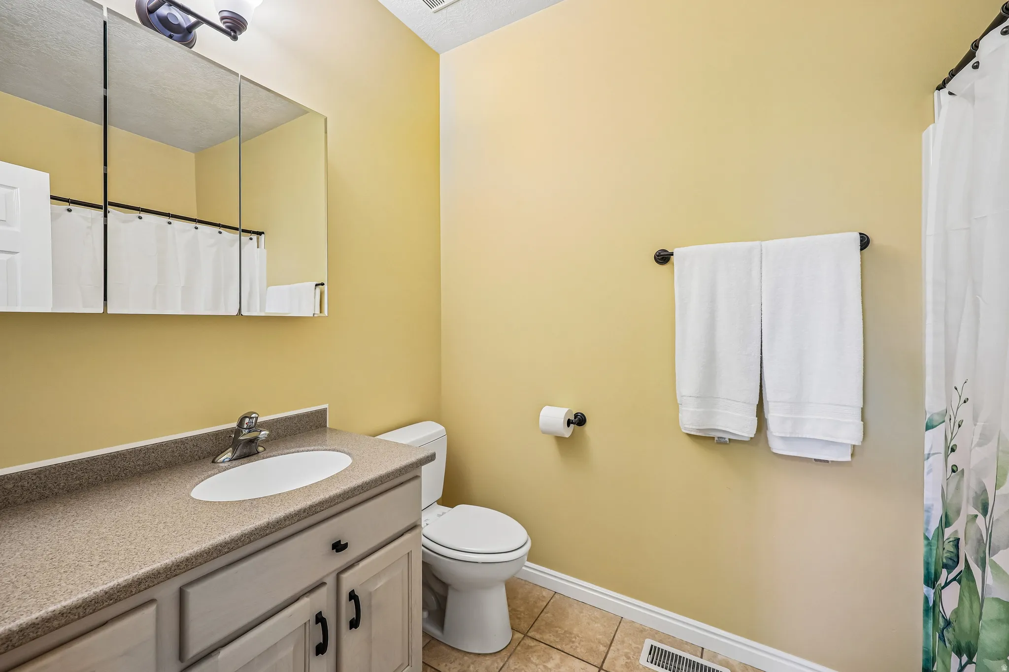 Bathroom featuring a single vanity with a laminate countertop, undermount sink, and brushed nickel faucet