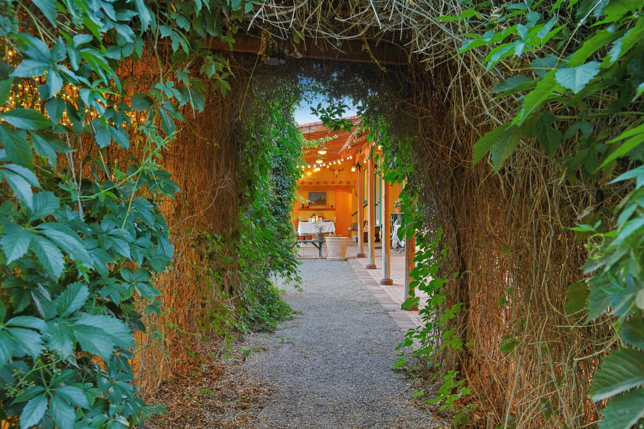 Gravel pathway leading to a covered patio area, framed by extensive natural foliage