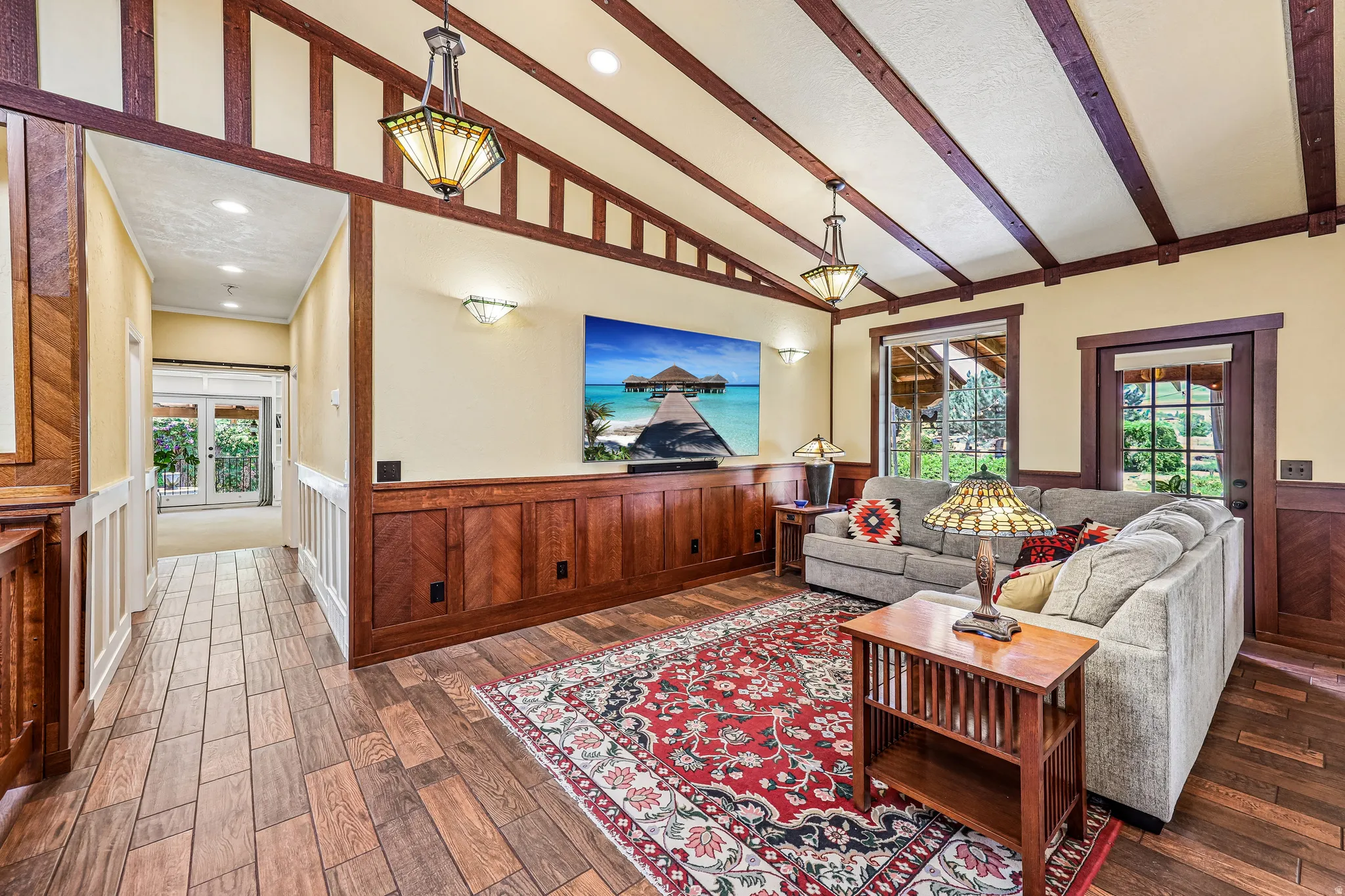 Vaulted ceiling with exposed wood beams, detailed wood wainscoting, wood-finish flooring, recessed lighting, and a glass-paned exterior door