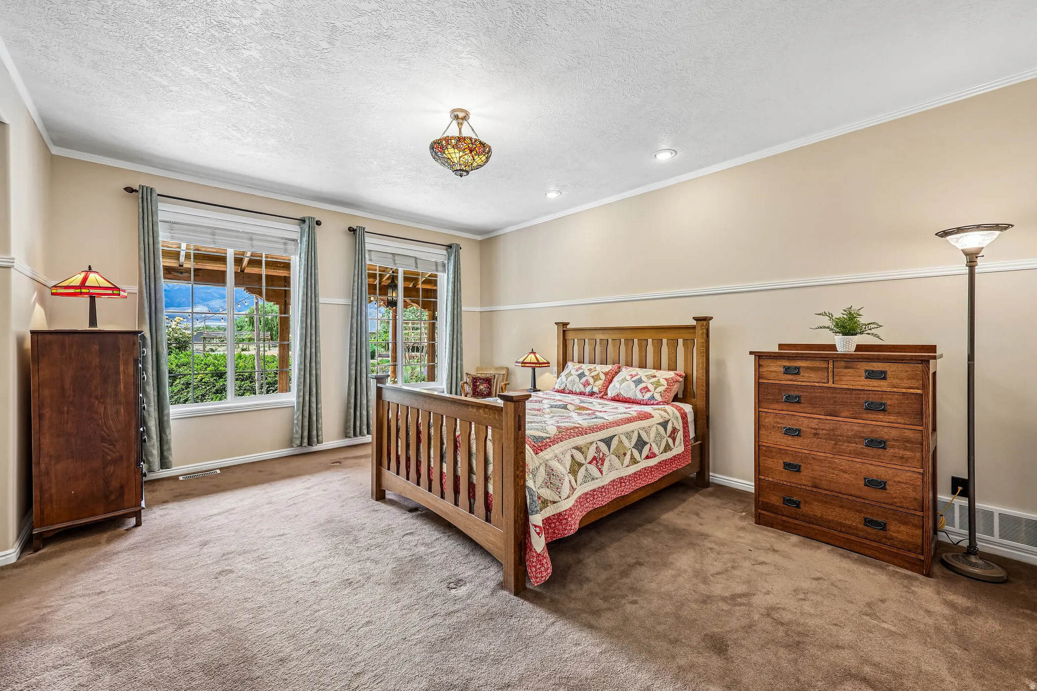 Expansive room featuring two large windows, textured beige walls with white trim, and a patterned ceiling