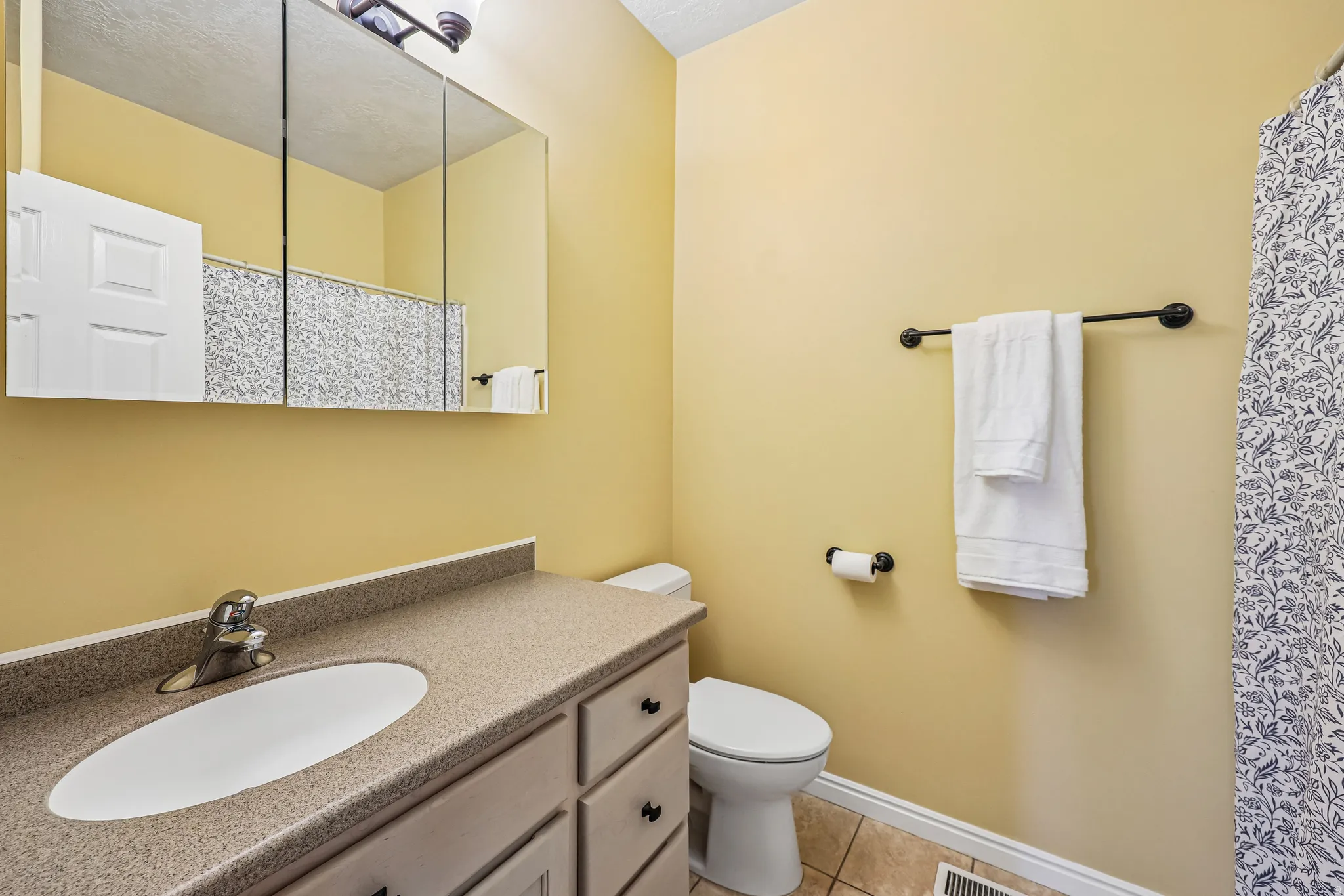 Bathroom featuring a single vanity with an integrated sink, a mirrored medicine cabinet, and tile flooring