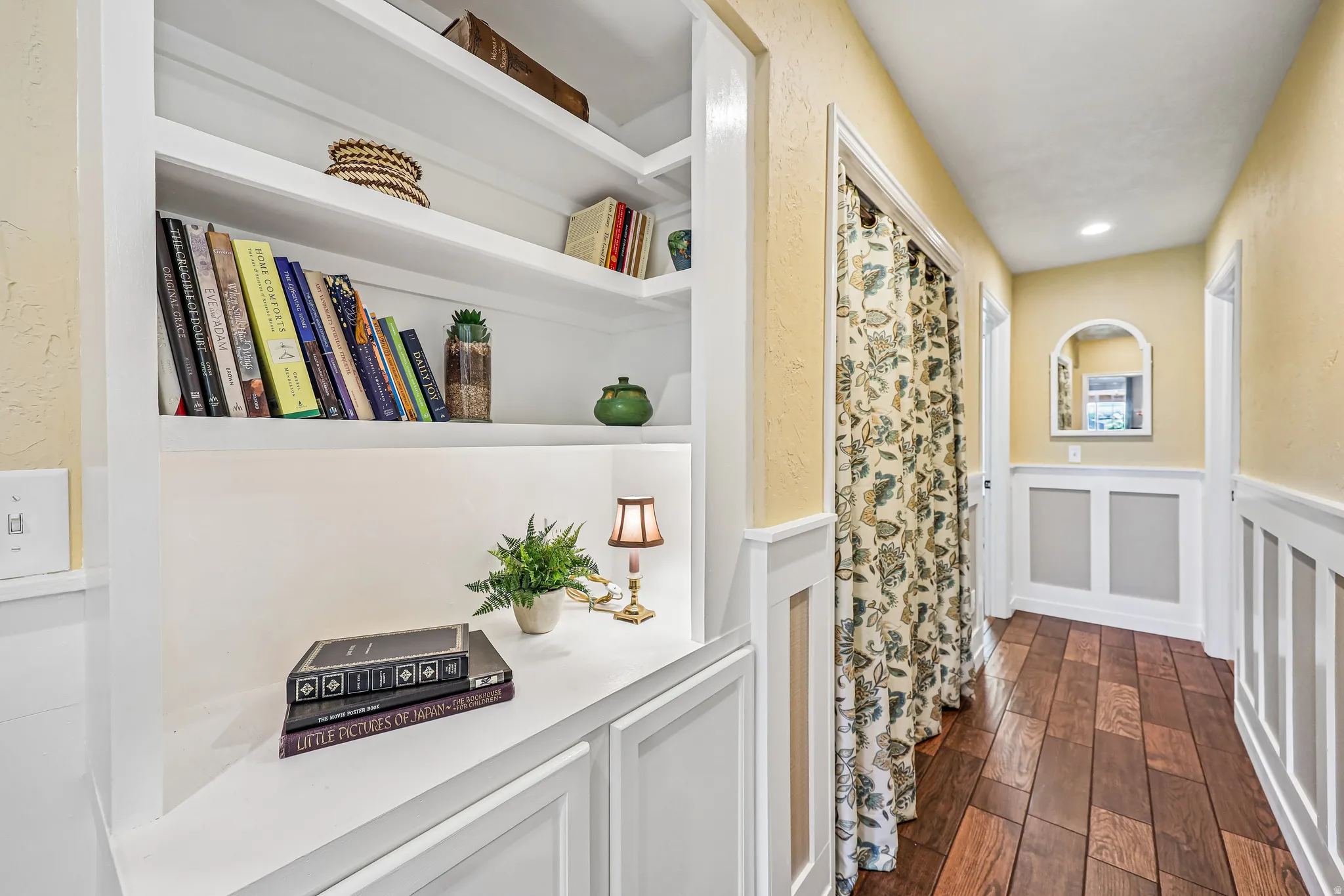 Hallway featuring recessed lighting, wood-finish flooring, white wainscoting, and built-in shelving with integrated cabinetry