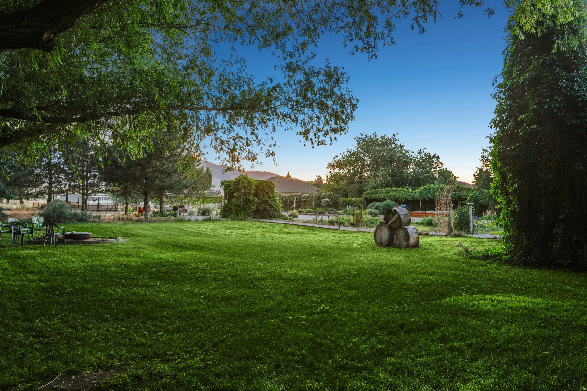 Expansive green lawn with mature trees and a dedicated fire pit area