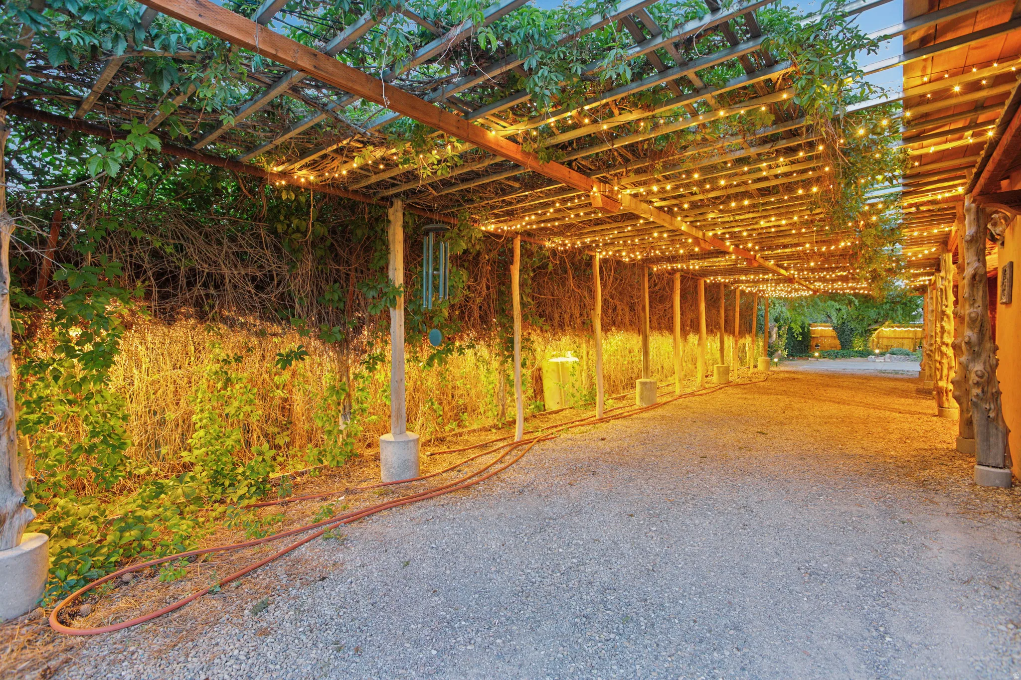 Expansive gravel pathway beneath a wood pergola with integrated string lighting