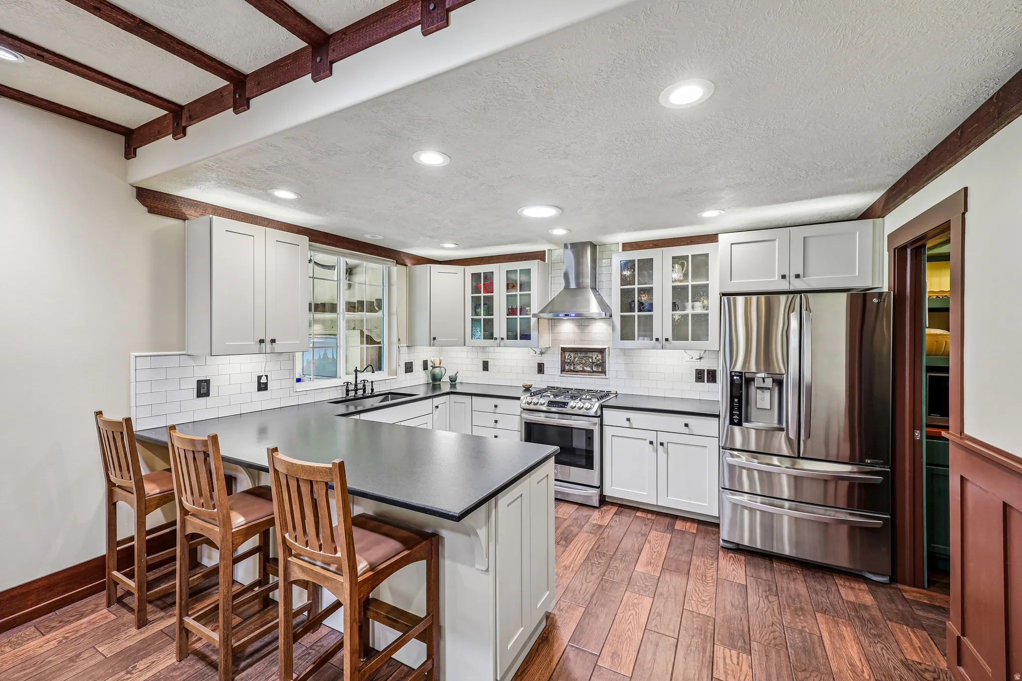 Contemporary kitchen featuring white shaker cabinetry, dark countertops, a subway tile backsplash, and stainless steel appliances