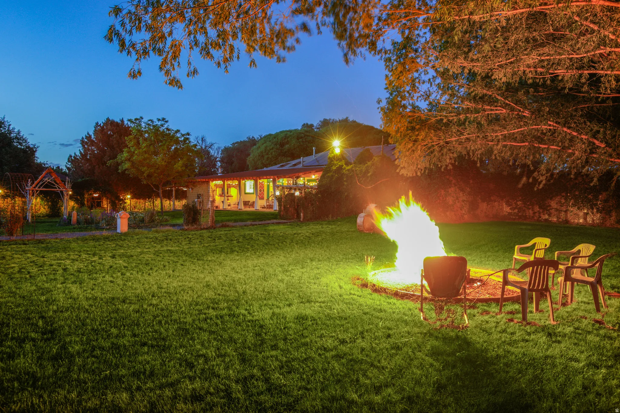 Spacious backyard featuring a manicured lawn, established trees, and a fire pit area