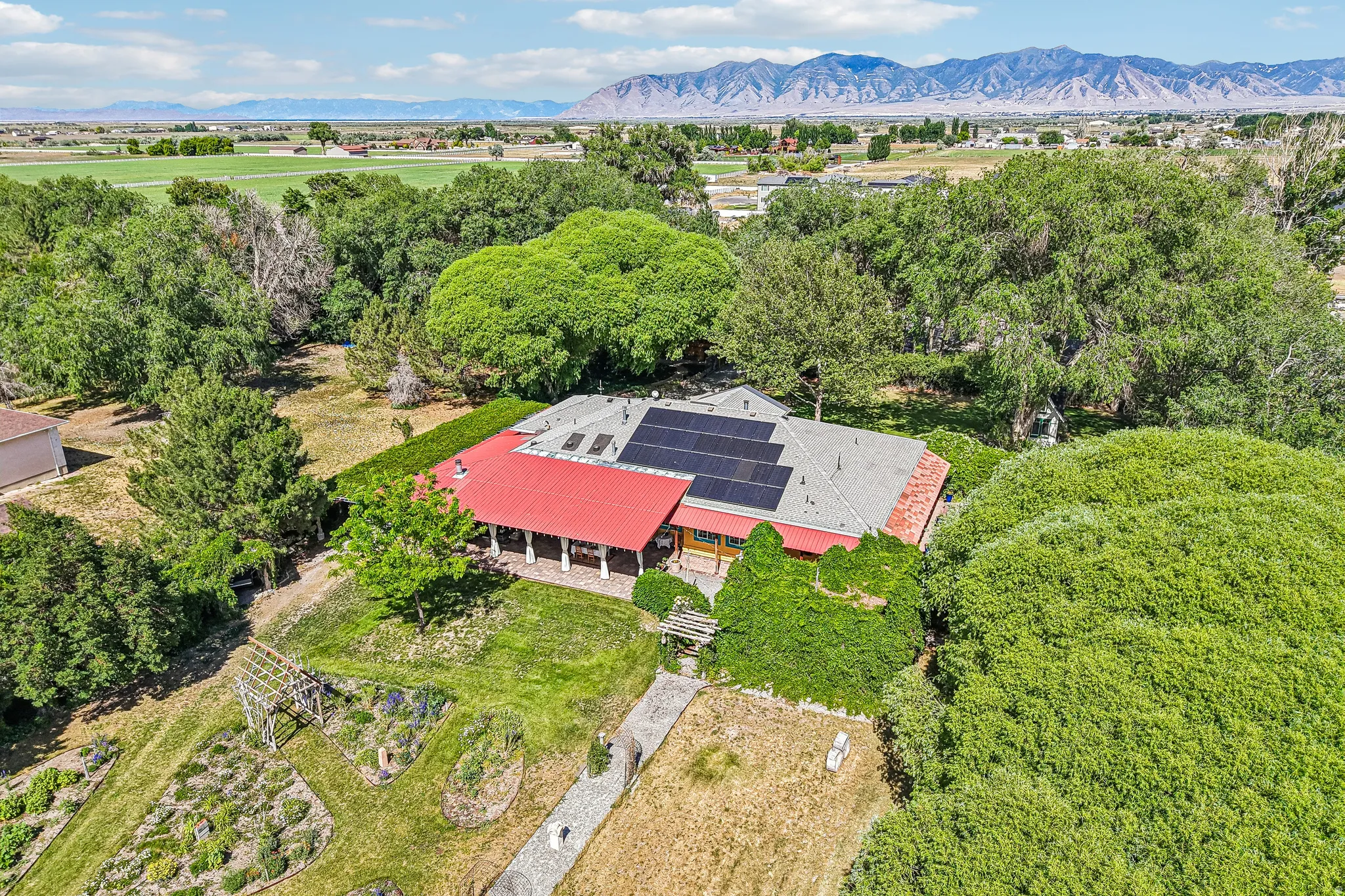 Red-pitched roof residence featuring solar panels and a covered patio with columns
