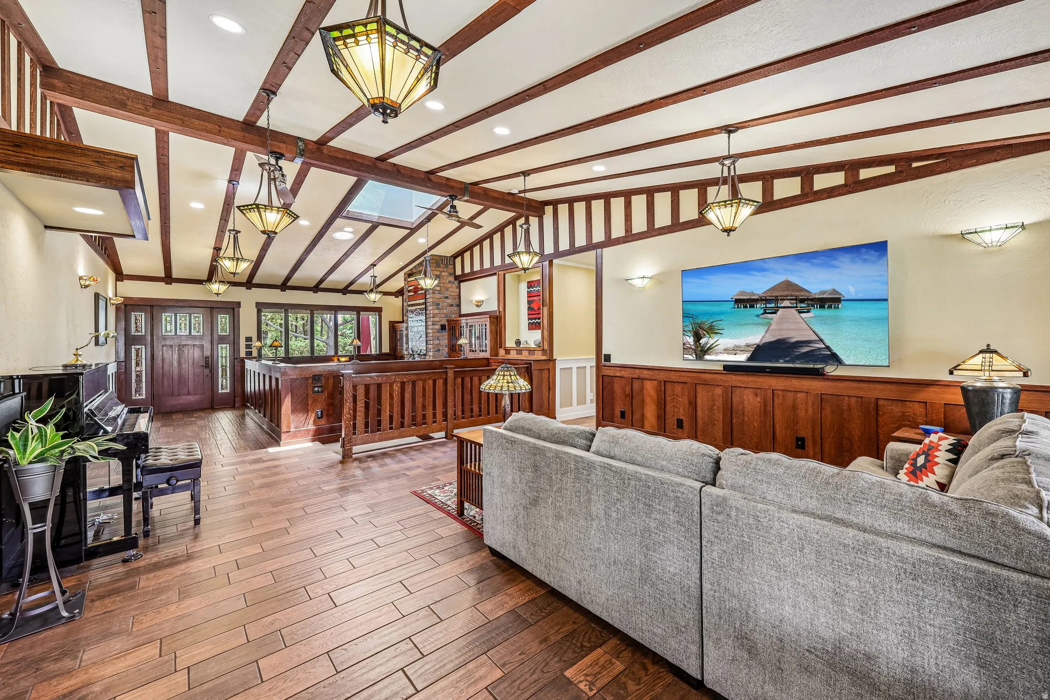 Spacious living area featuring wood-finish flooring, vaulted ceilings with exposed beams, and multiple skylights