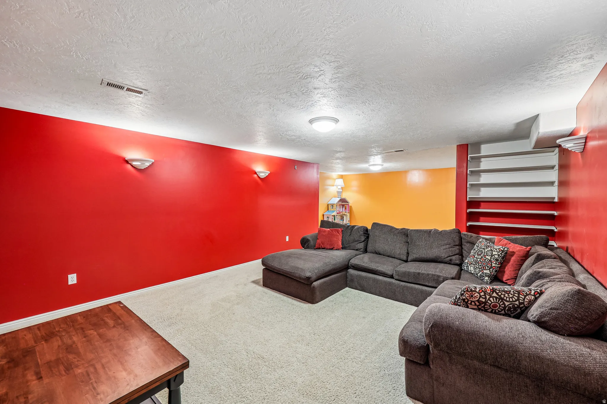 Finished lower level featuring textured ceilings, recessed lighting, wall sconces, and built-in shelving