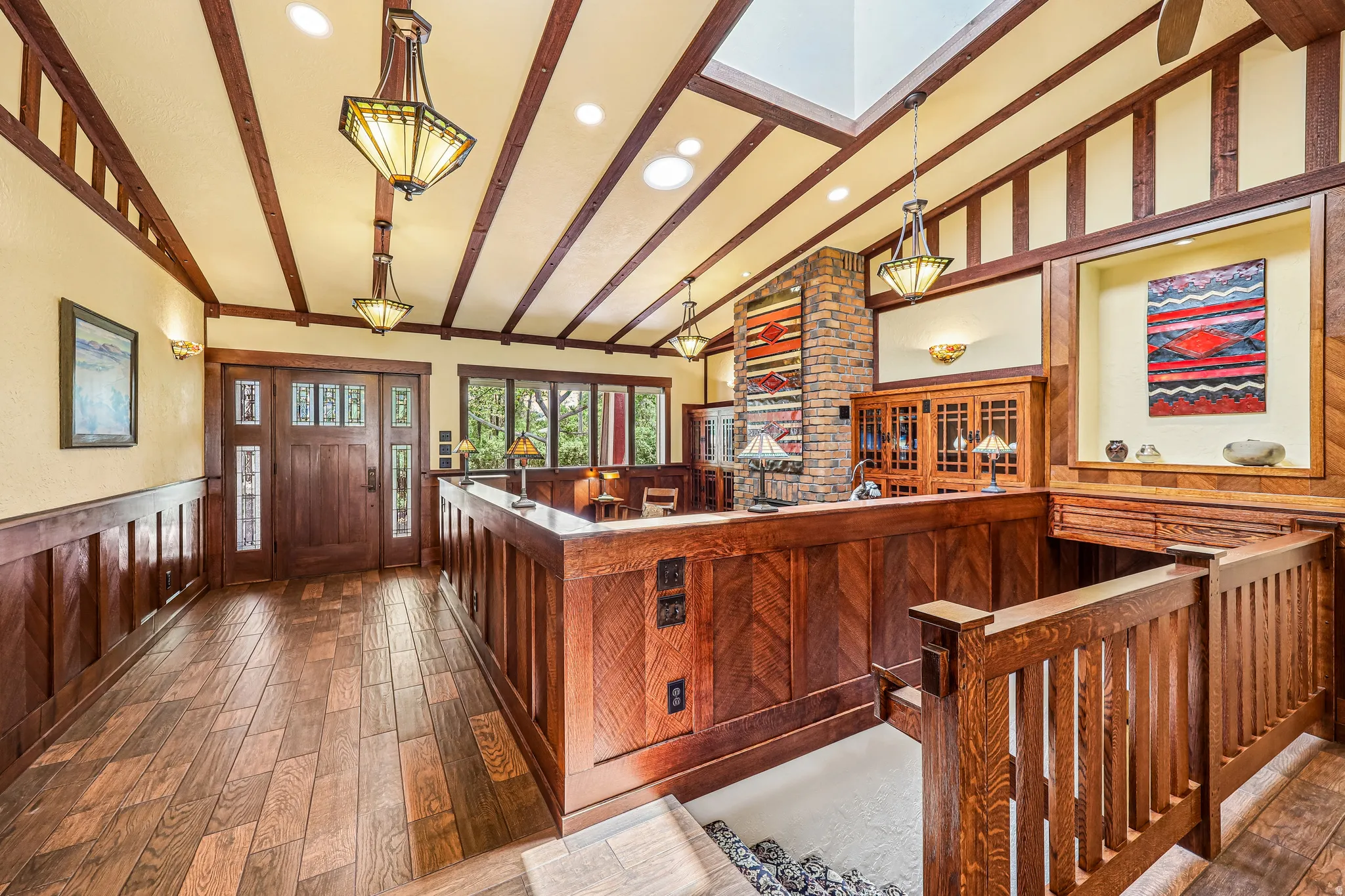 Entryway featuring wood-finish flooring, a solid wood entry door with decorative glass, and extensive wood paneling and trim