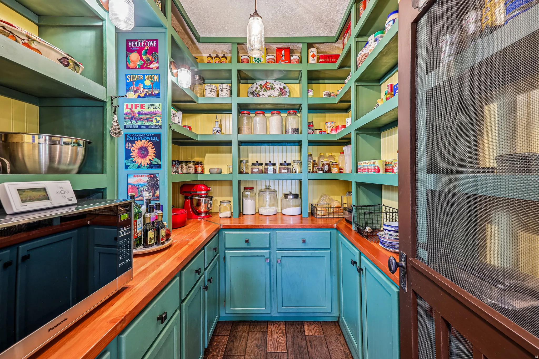 Pantry featuring extensive built-in shelving, wood-finish countertops, lower cabinetry, and wood-finish flooring