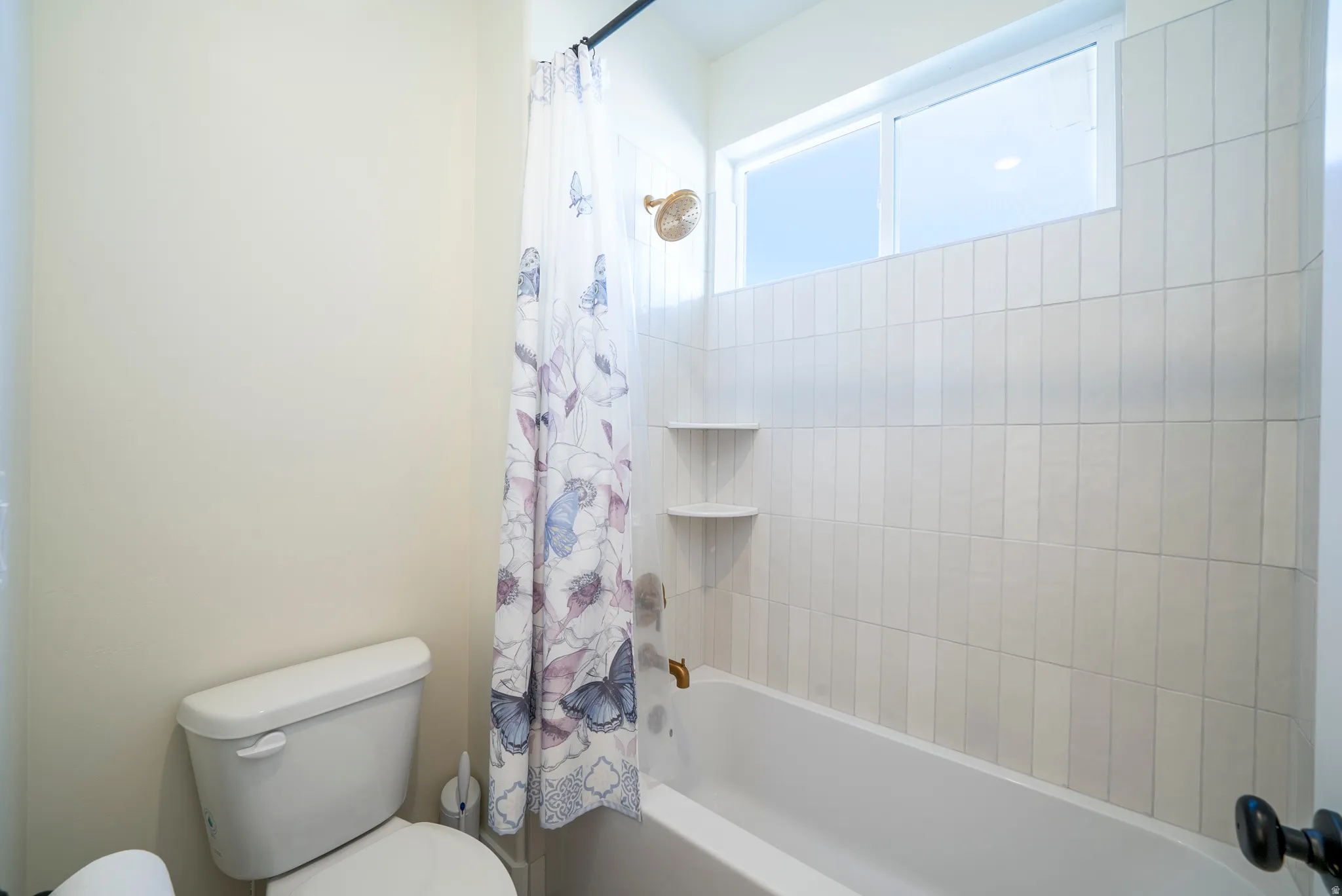 Bathroom with a white toilet and a tub-shower combination