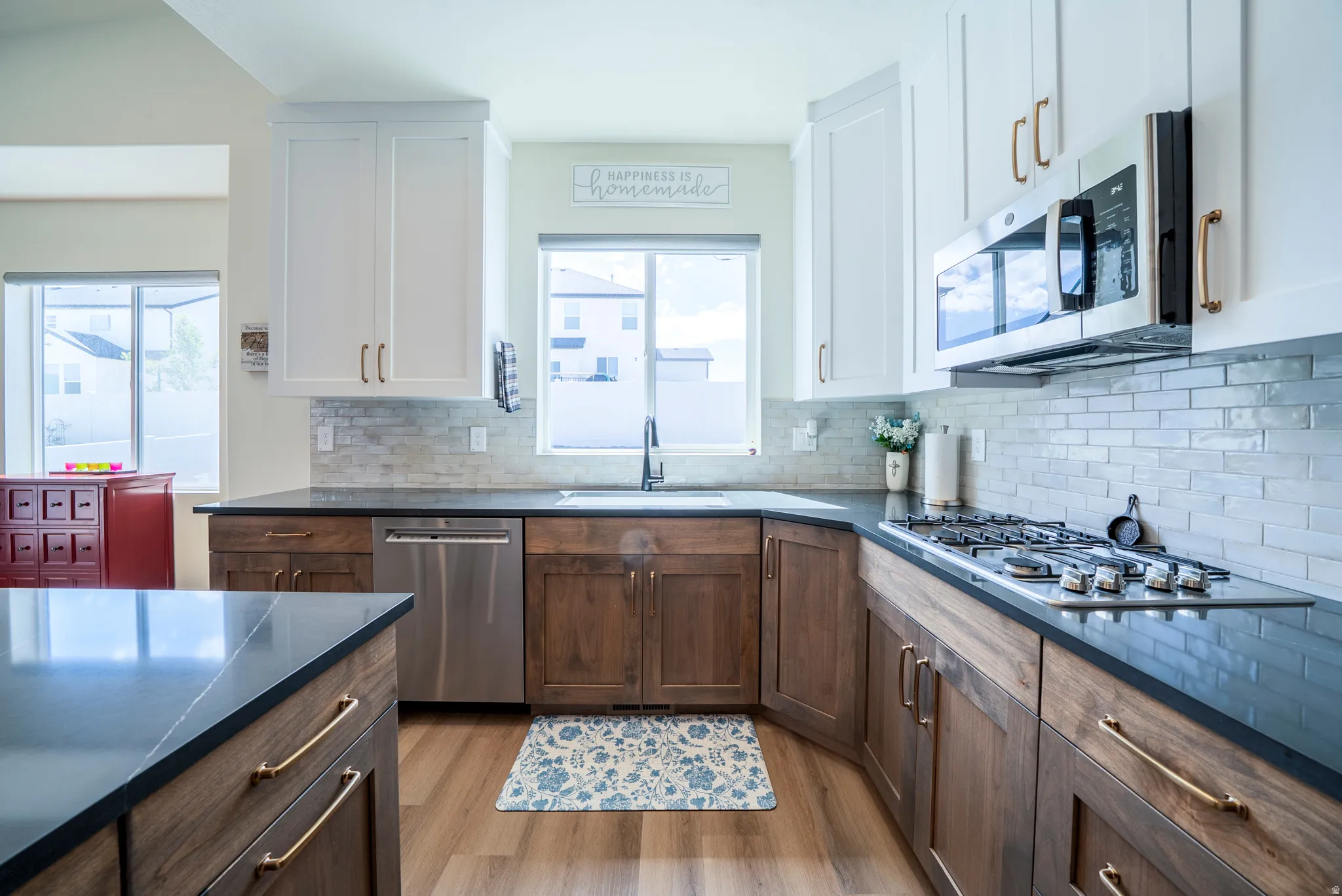 Contemporary kitchen featuring white upper cabinetry, rich wood-finish lower cabinetry, and dark countertops