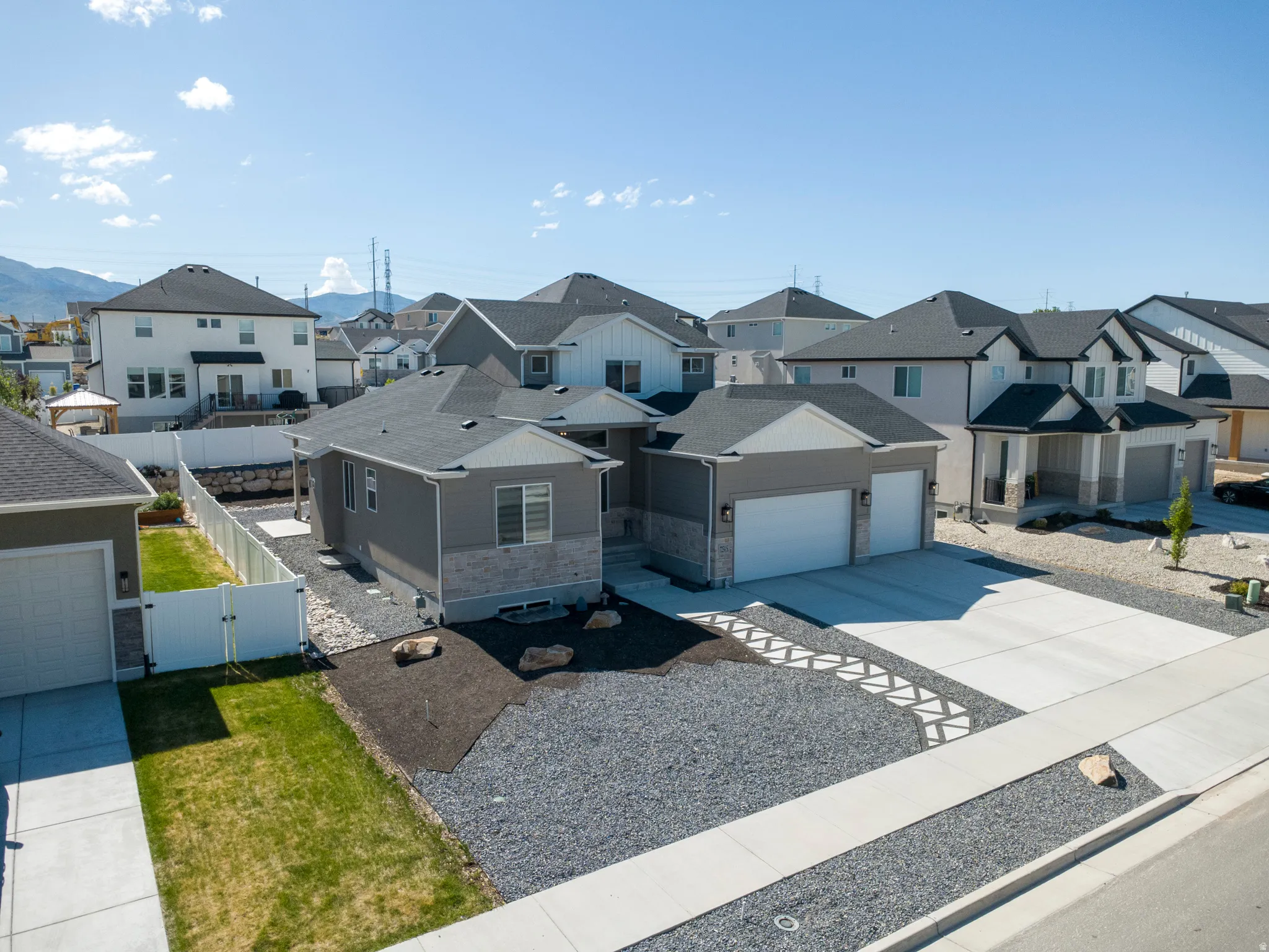 Contemporary residence with a two-car garage, stone and siding exterior, concrete driveway, and gravel landscaping