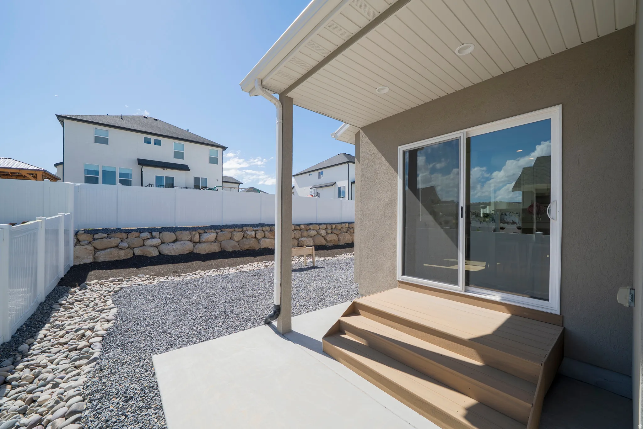Backyard patio featuring concrete flooring, wood-finish steps, and a sliding glass door