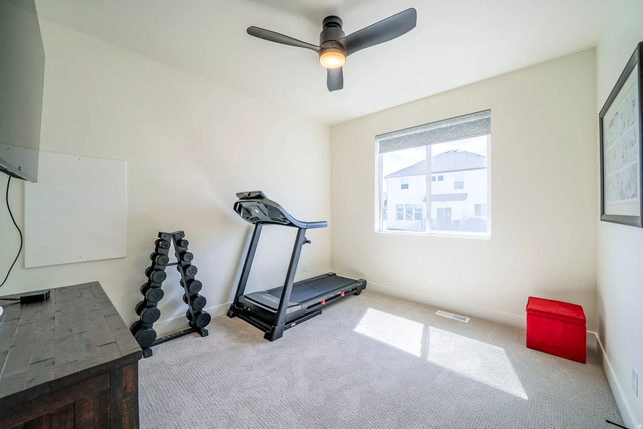 Carpeted room with a contemporary ceiling fan, large window, and light-toned walls