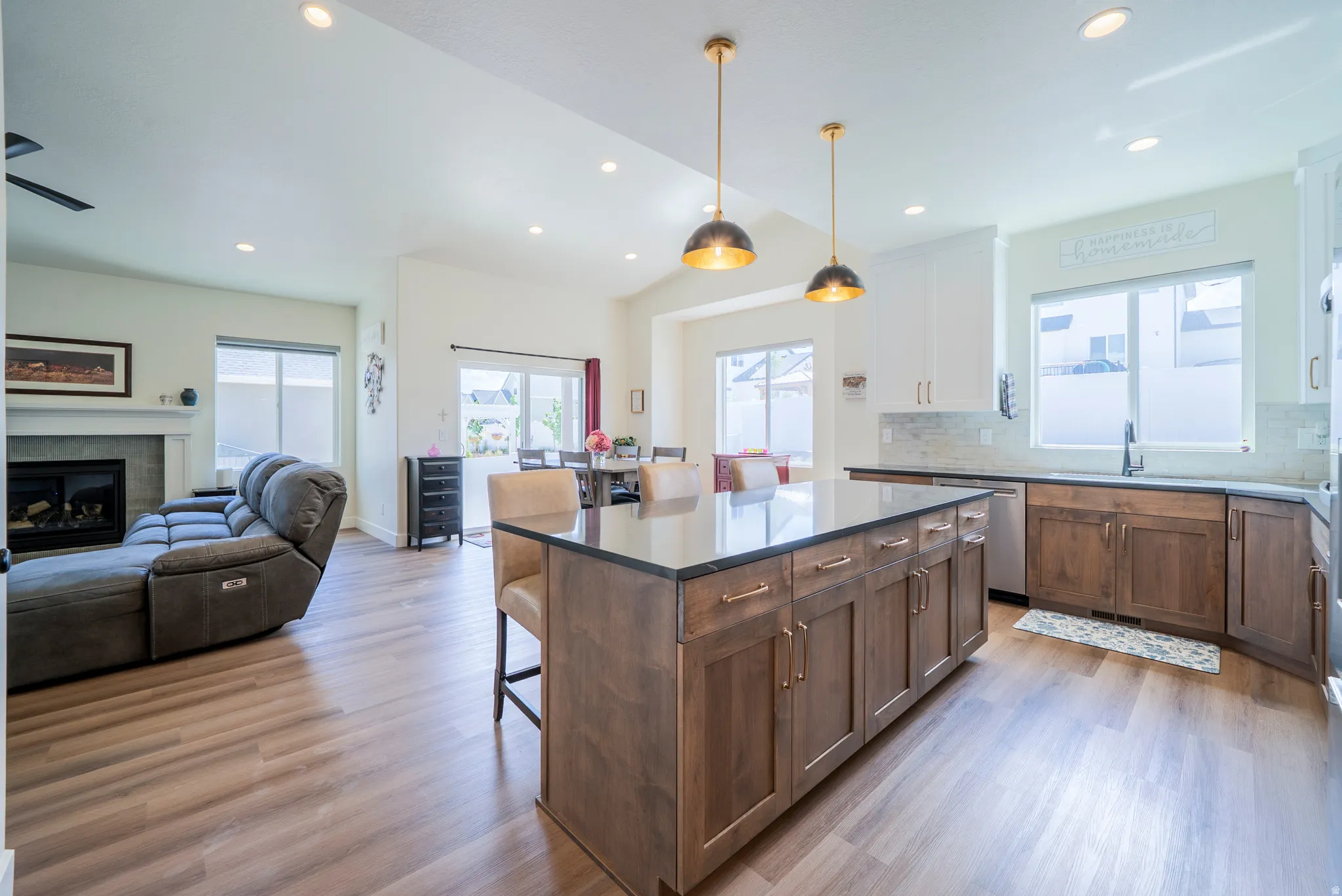 Spacious kitchen featuring a large central island with seating, dark countertops, and wood-finish flooring