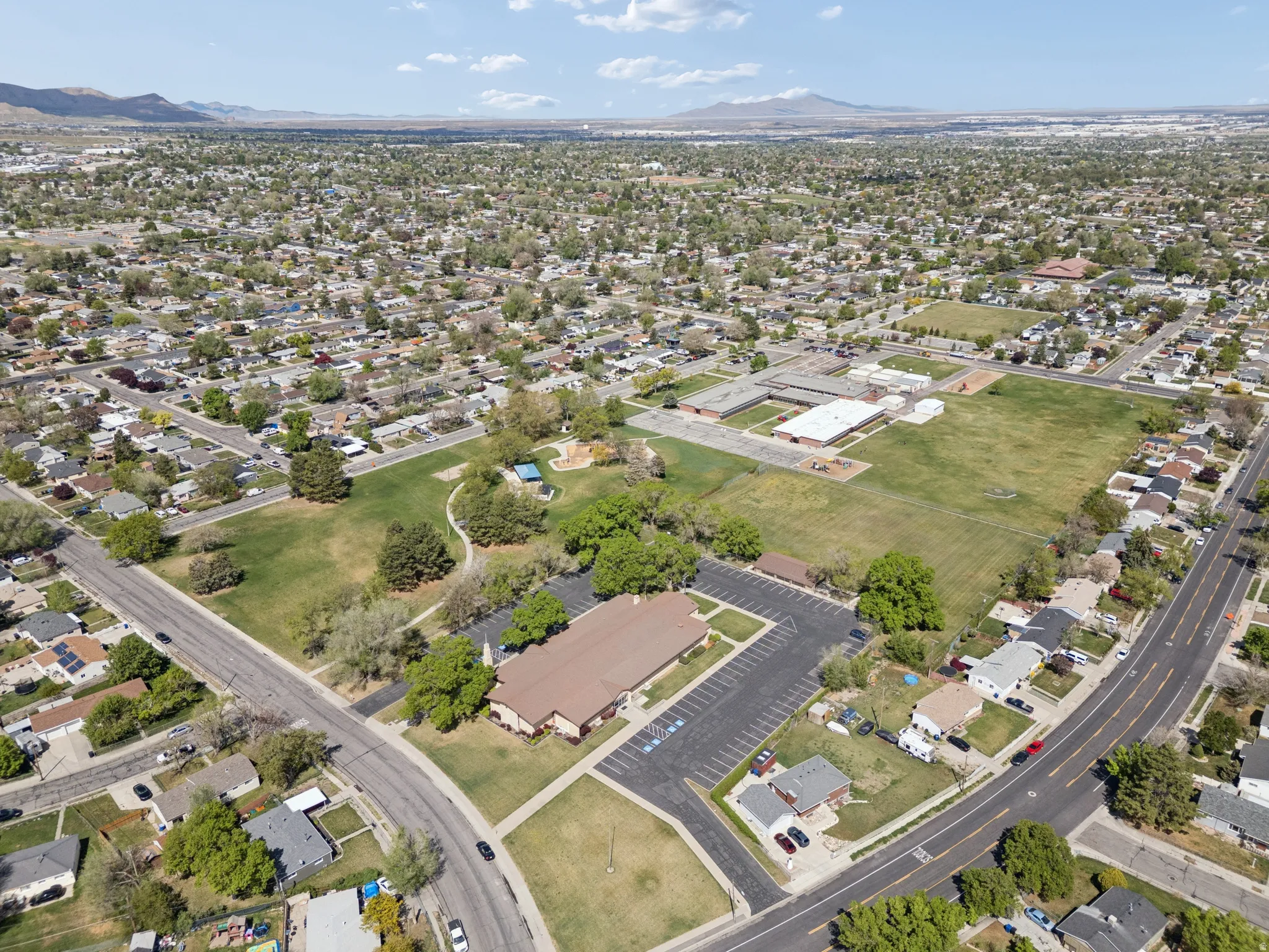 Residential neighborhood featuring mature trees, paved streets, and a large green space.