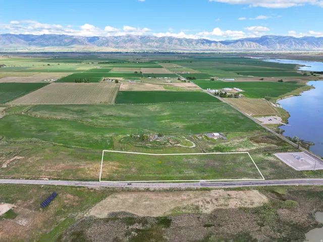 Expansive undeveloped land parcel outlined in white, featuring proximity to a body of water and a paved roadway