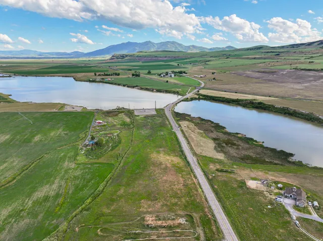 Expansive land parcel featuring two distinct bodies of water, a paved road traversing the property, and distant mountains