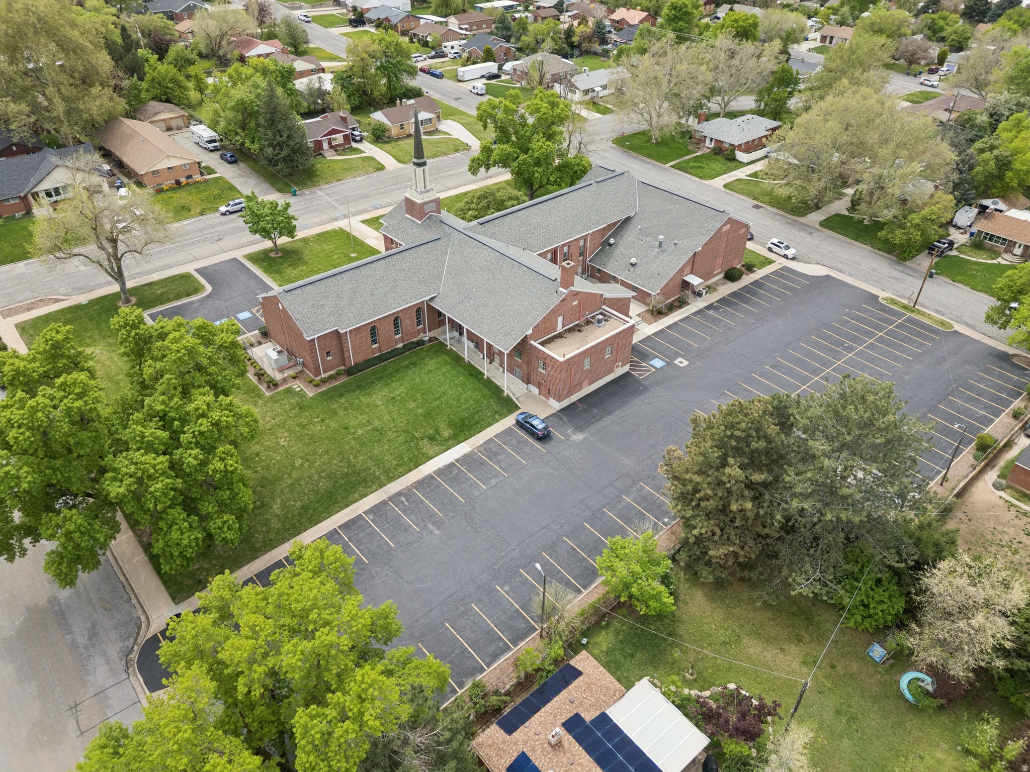Brick building with a steeple and a large asphalt parking lot.