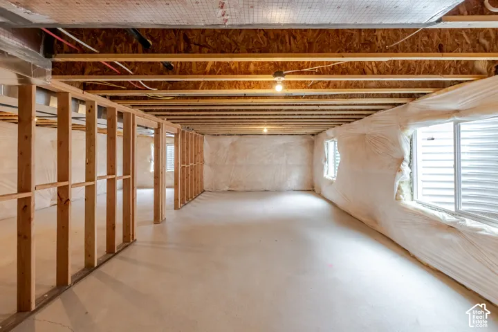 Unfinished lower level featuring exposed wood-stud framing, concrete flooring, insulated foundation walls, and inset windows