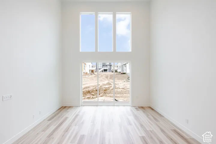 Double-height ceiling, large vertical windows, wood-finish flooring, and glass sliding doors