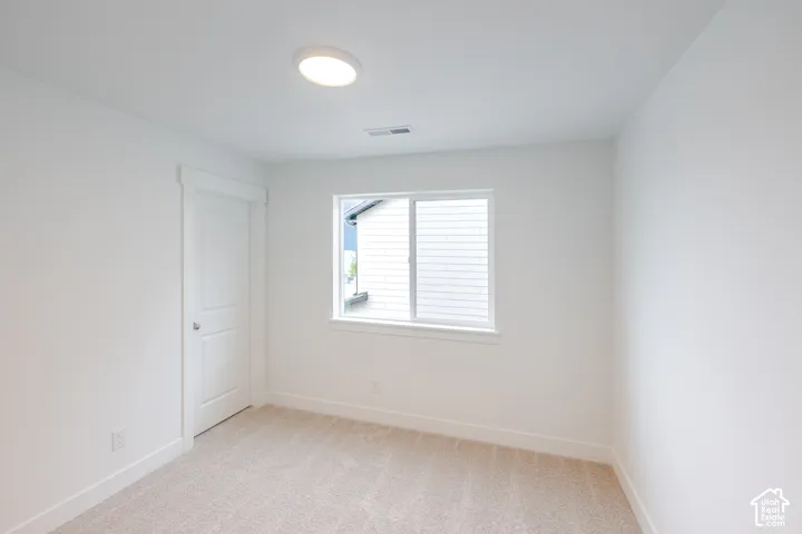 Neutral-toned carpeted flooring, white interior walls, flush-mount lighting, and a single-pane sliding window