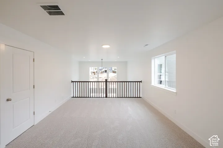 Neutral-toned wall-to-wall carpeting, black metal baluster railing, recessed ceiling lighting, and a single-panel interior door