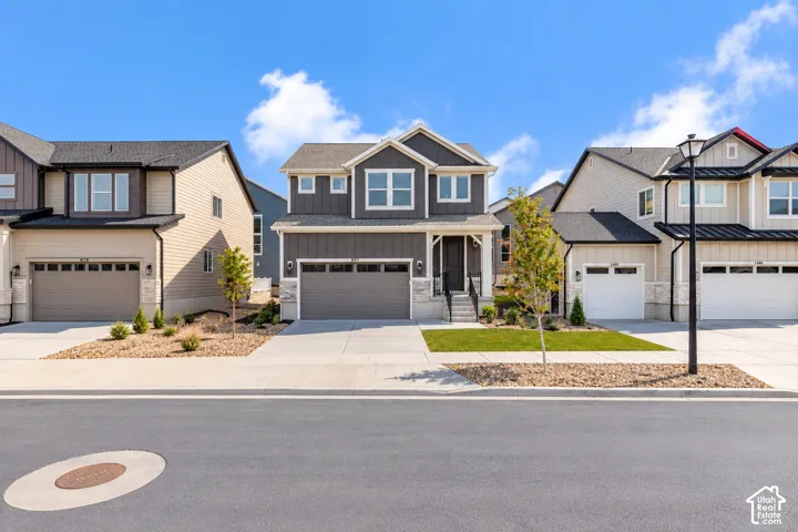 Two-story residence featuring vertical siding, stone veneer accents, an attached two-car garage, asphalt shingle roofing, and a concrete driveway