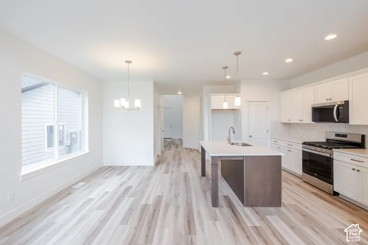 Kitchen featuring white shaker-style cabinetry, wood-finish flooring, a central island with a stone-surface countertop, recessed lighting, and stainless steel appliances