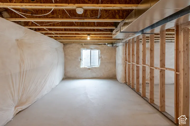 Unfinished space featuring exposed timber framing, concrete flooring, exterior-grade vapor barrier insulation, and a single egress window