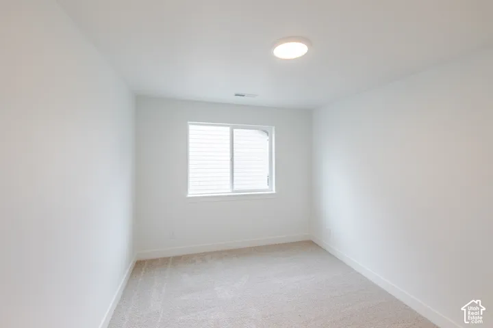 Neutral-toned interior space featuring crisp white walls, wall-to-wall carpeting, a horizontal sliding window, and a flush-mount ceiling light fixture