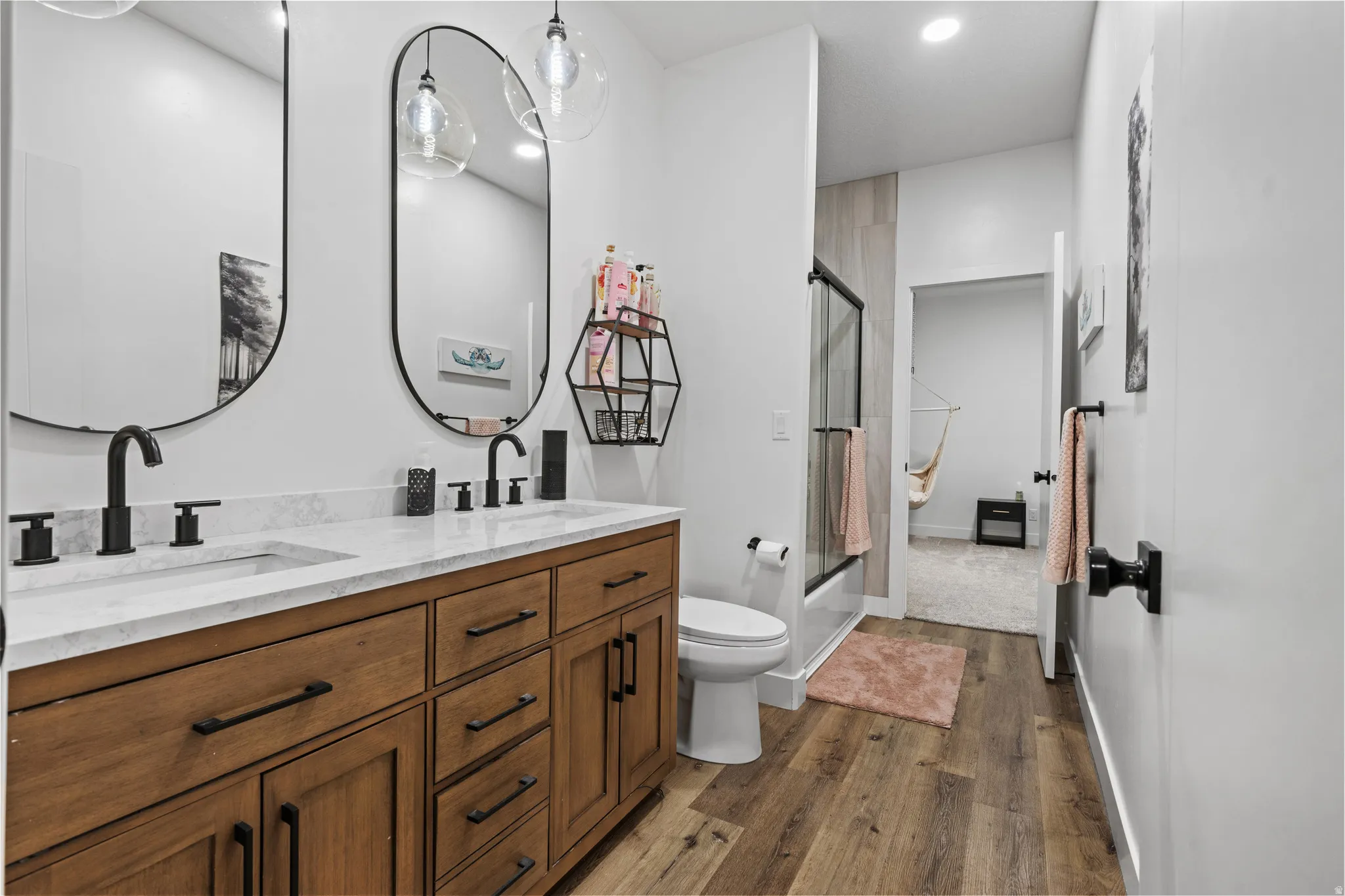 Dual vanity with a light-colored countertop, wood-finish cabinetry, and matte black fixtures