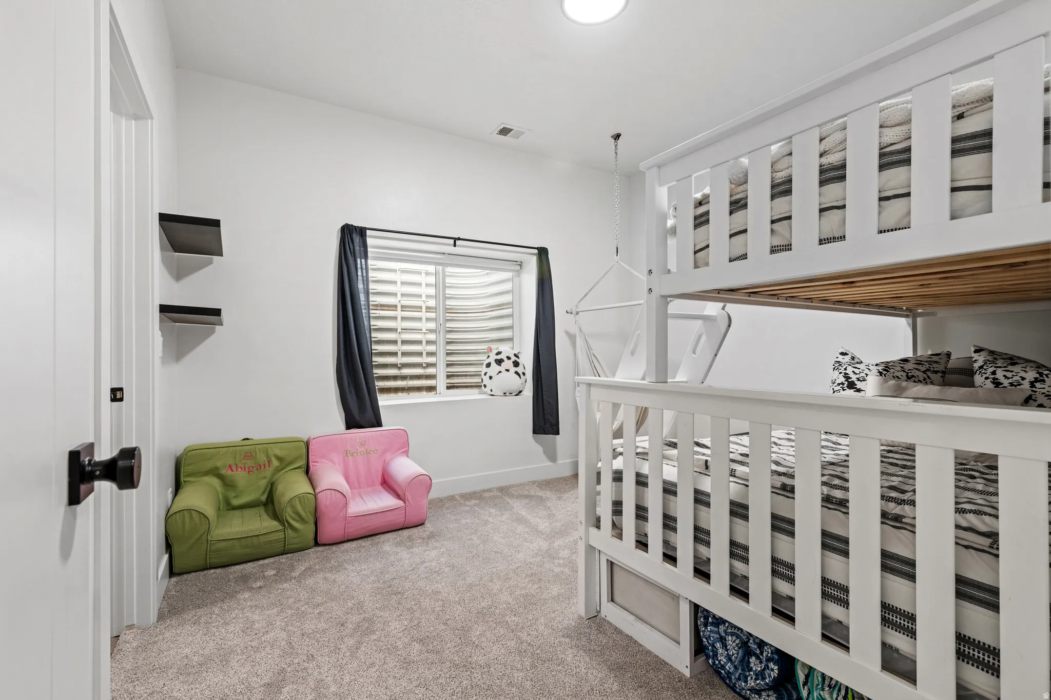 Spacious room featuring white walls and a light-toned carpeted floor