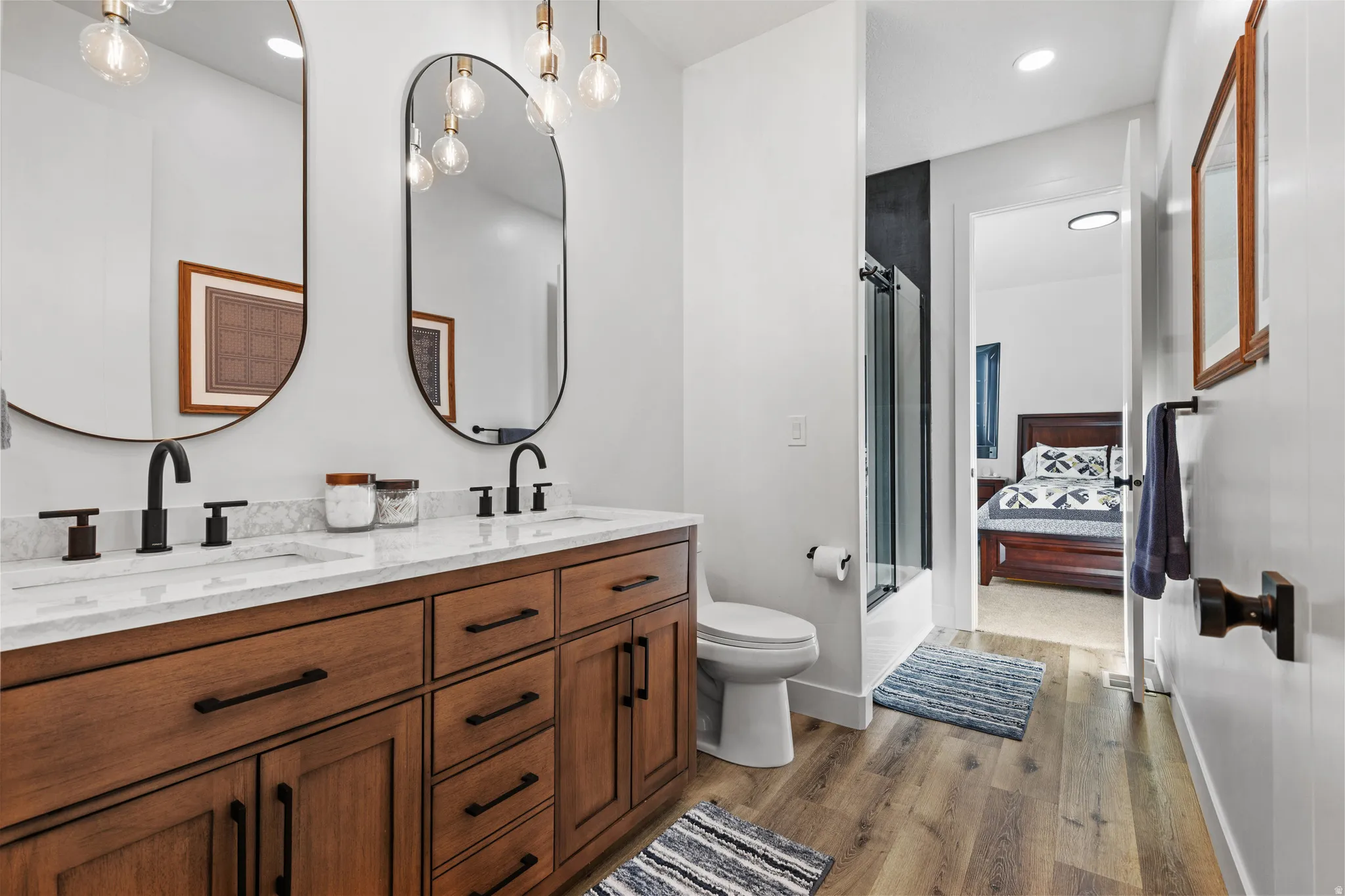 Dual vanity featuring wood-finish cabinetry, white countertop, and matte black fixtures