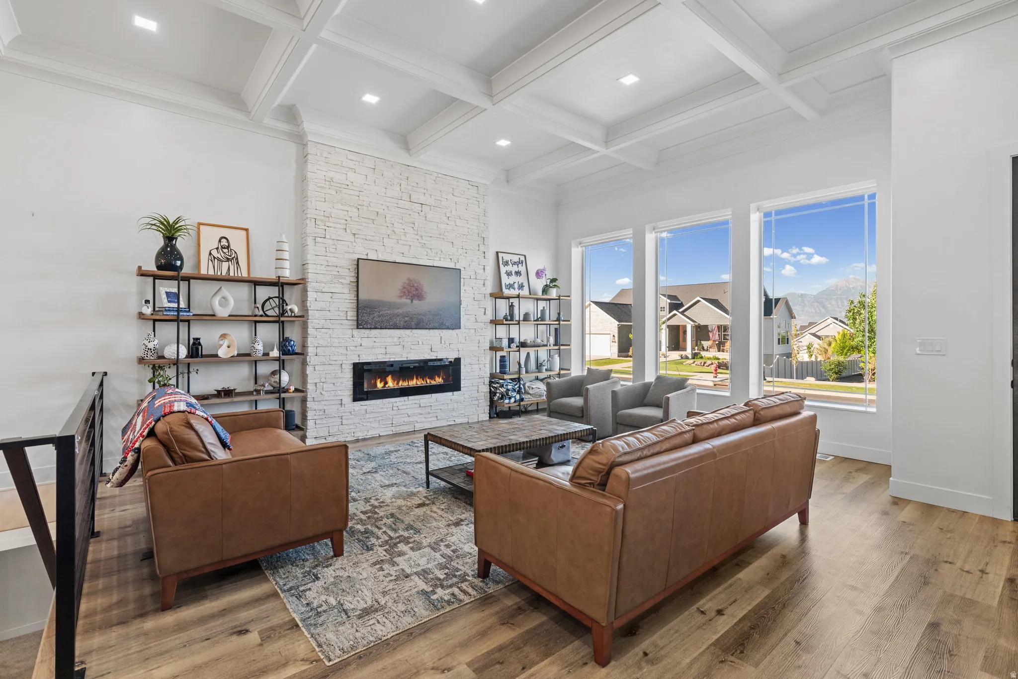 Spacious living area featuring a coffered ceiling, a white stacked stone fireplace with a linear insert, and wood-finish flooring