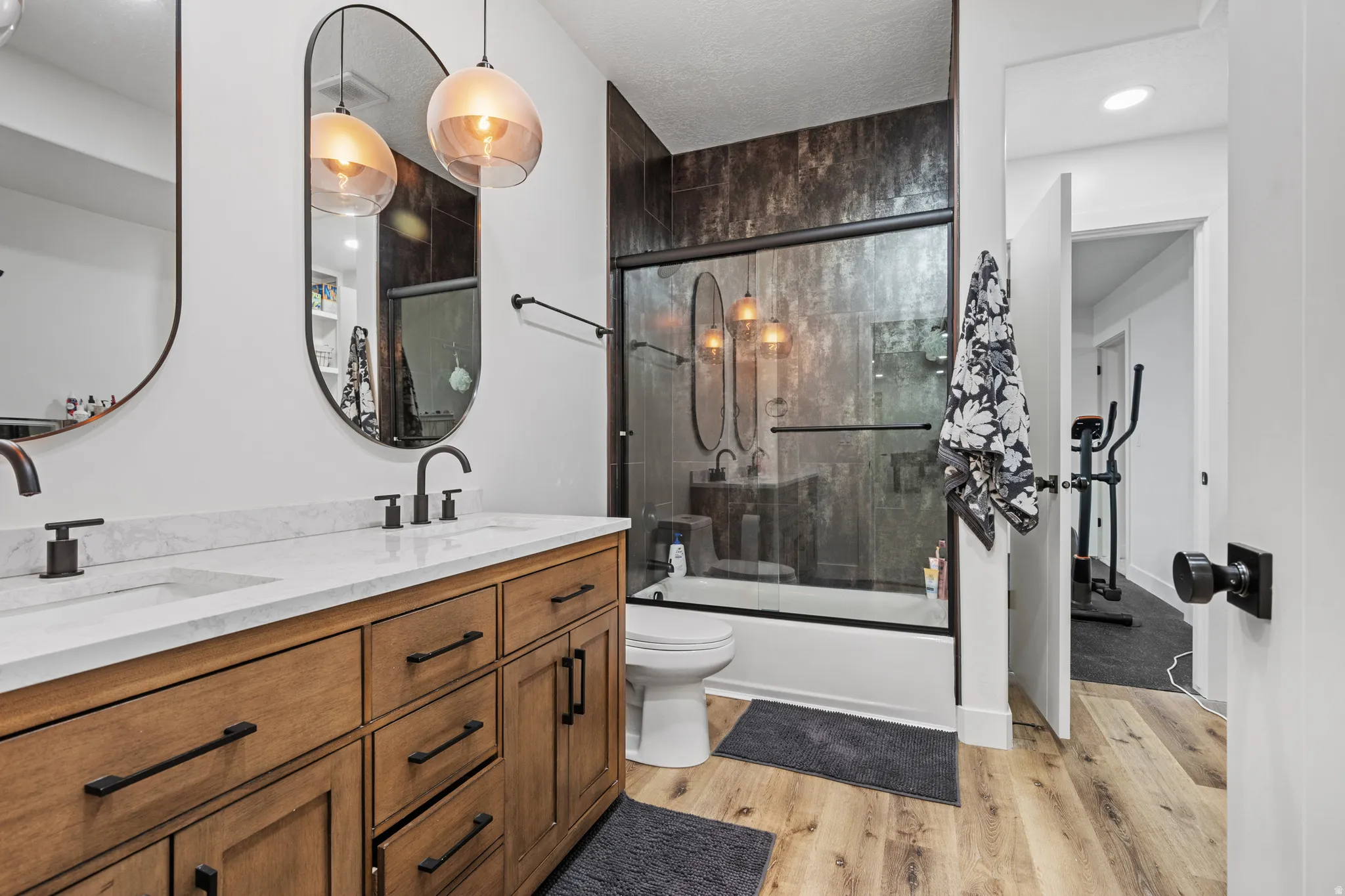 Dual vanity with wood-finish cabinetry, white countertop, and matte black fixtures
