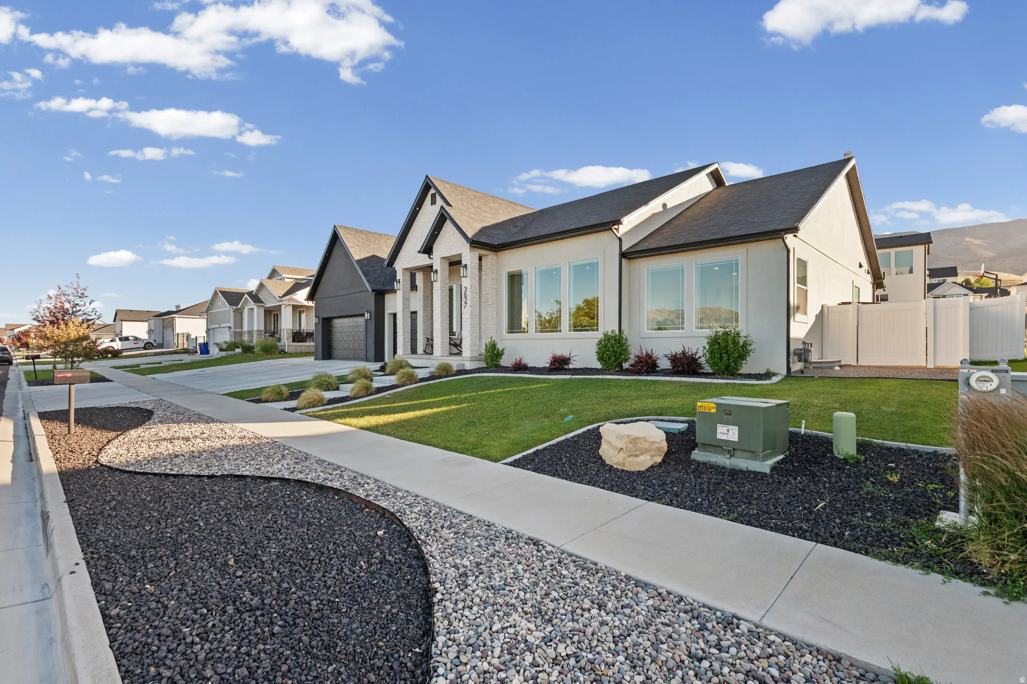 Modern residence featuring a light-colored stucco exterior with dark trim accents