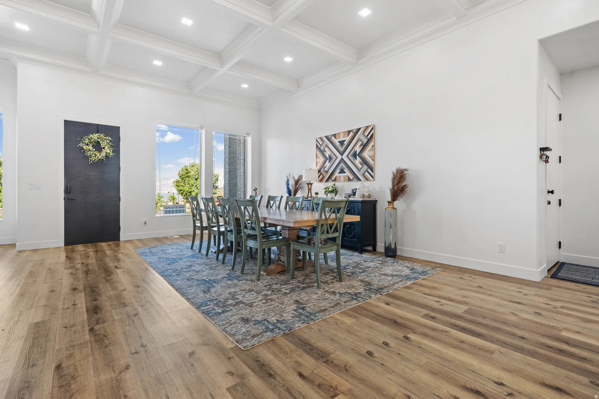 Expansive interior space featuring wood-finish flooring, a coffered ceiling with recessed lighting, and large windows