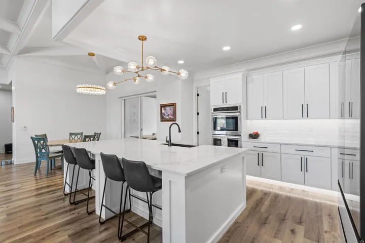 Expansive kitchen island with a stone countertop and integrated sink, complemented by wood-finish flooring