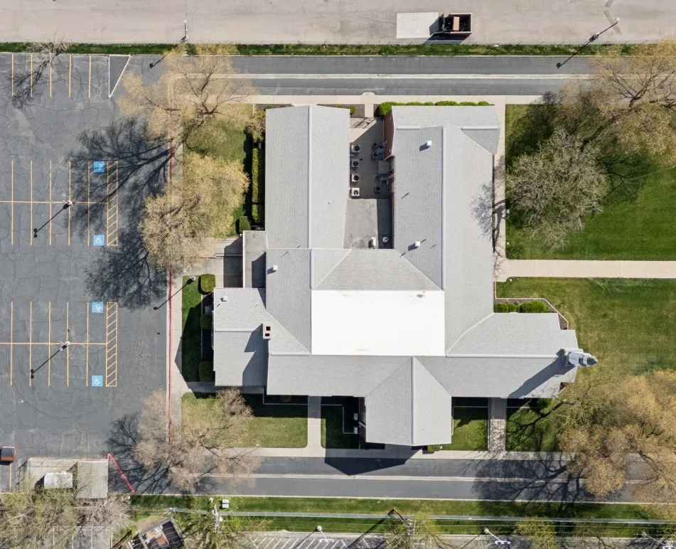 Expansive property featuring a large asphalt parking lot, surrounding green spaces, and mature trees.