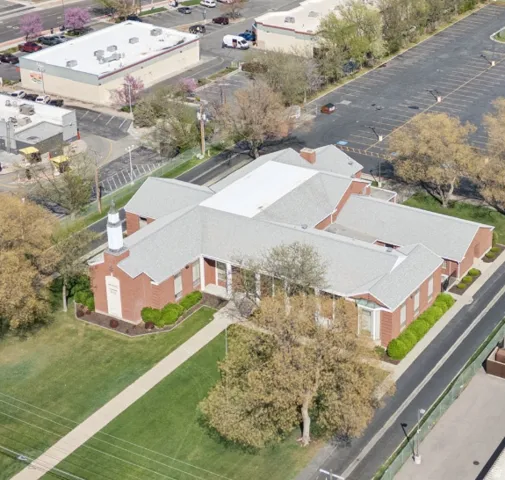 Brick commercial building featuring a steeple, multiple entryways, and a shingle roof