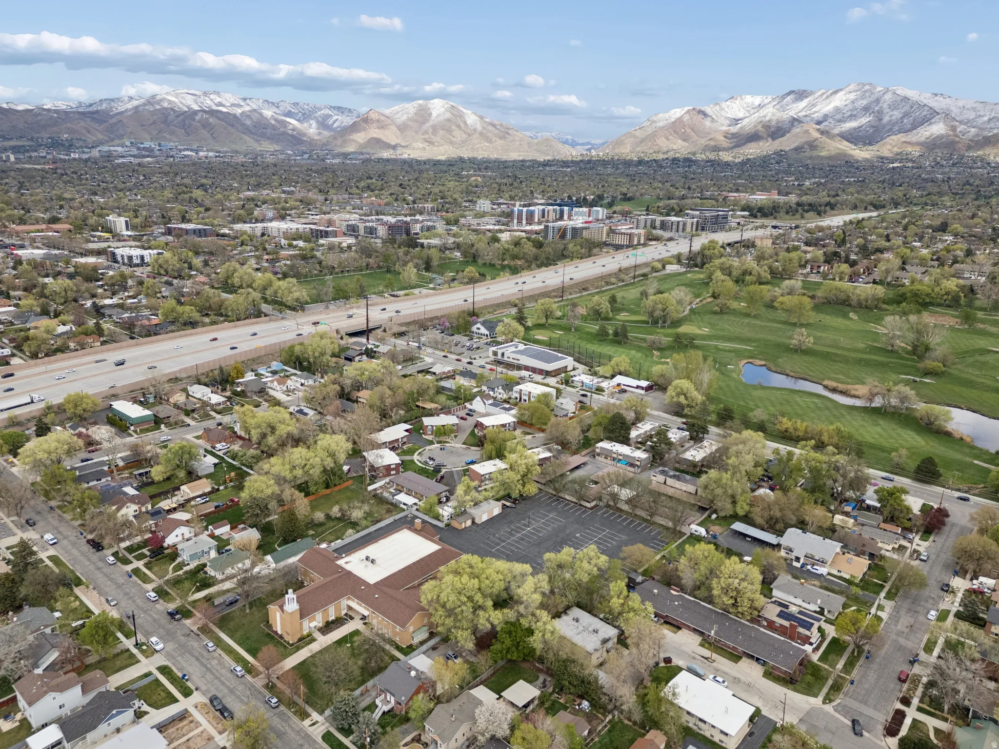 Aerial perspective showcasing a residential area with varied housing, mature trees, and a prominent interstate.