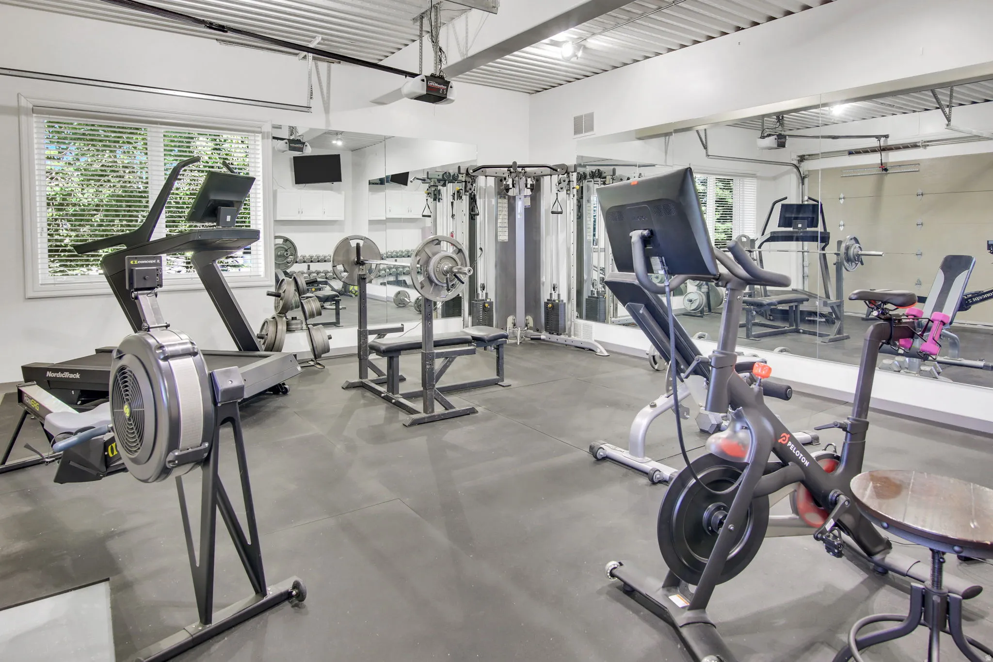 Dedicated fitness area featuring durable rubber flooring, expansive wall-mounted mirrors, and a white corrugated ceiling