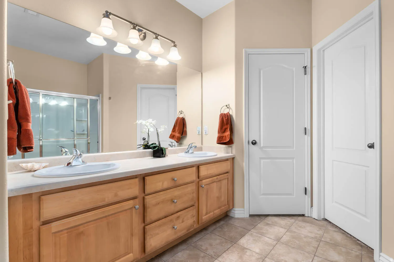 Dual vanity with light wood-finish cabinetry, integrated sinks, and polished chrome faucets
