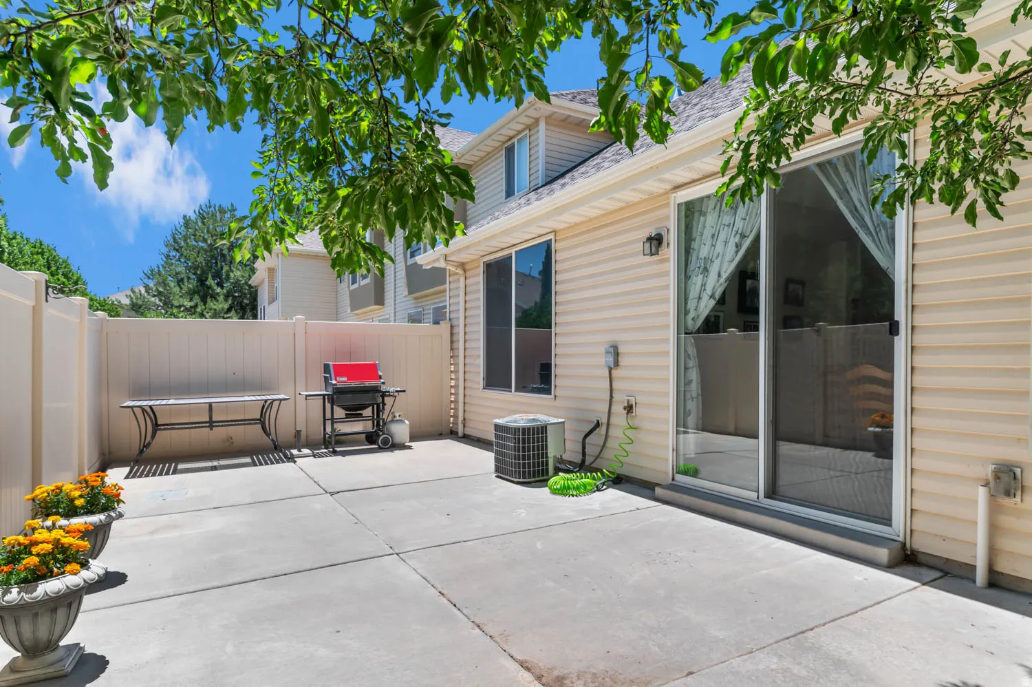 Private concrete patio bordered by a light-colored privacy fence