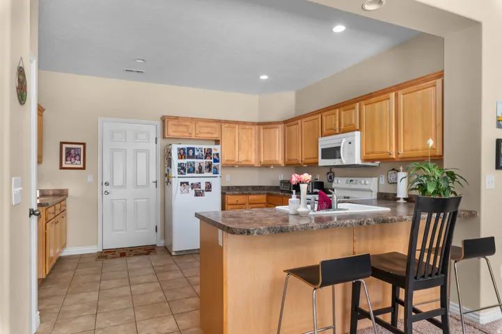 Kitchen featuring wood cabinetry, stone-finish countertops, tile flooring, and recessed lighting