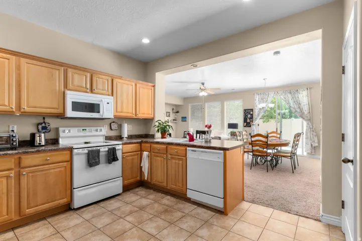 Kitchen with wood cabinetry, dark countertops, and tile flooring
