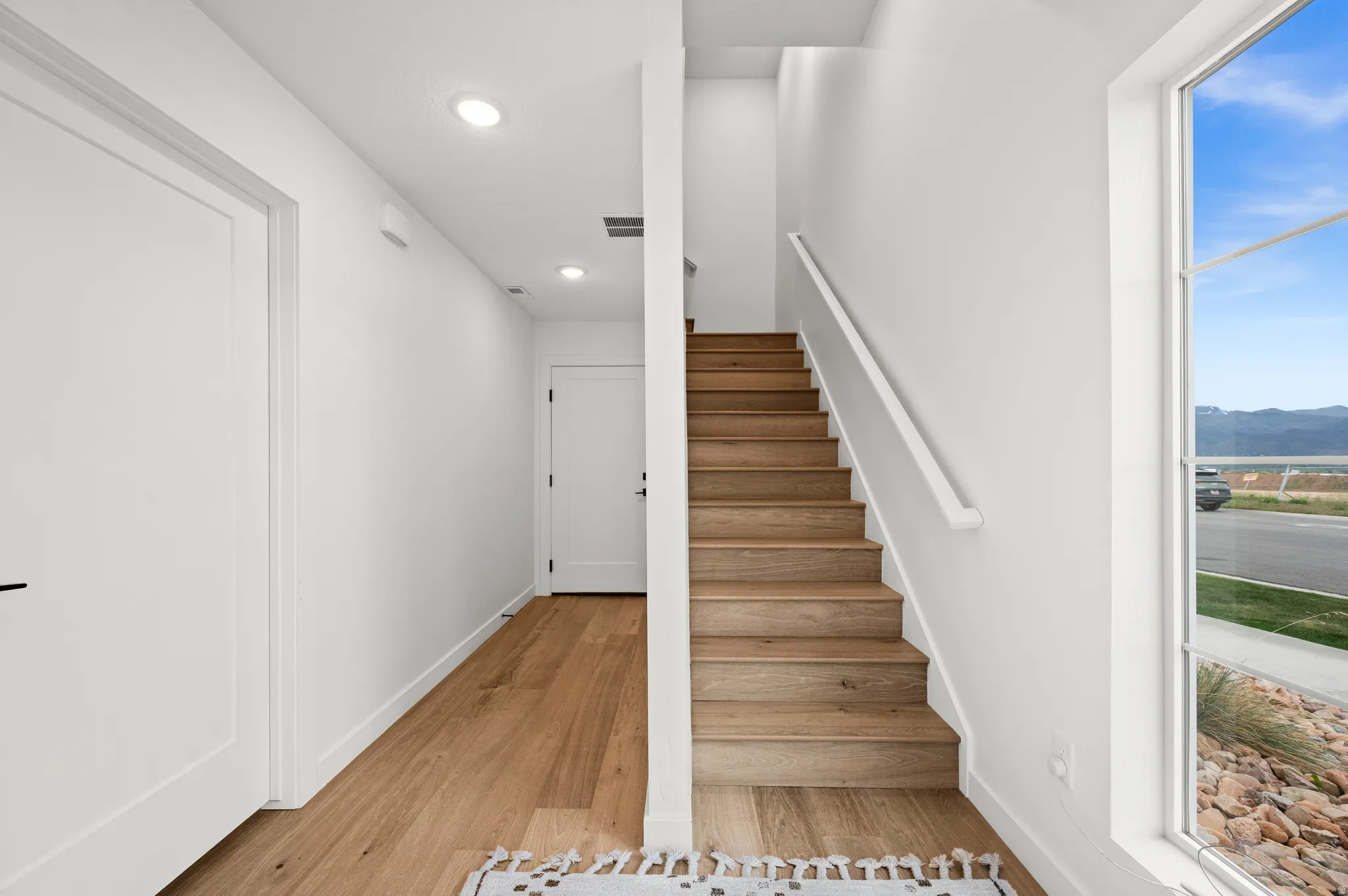 Staircase featuring wood-finish treads and a clean white handrail